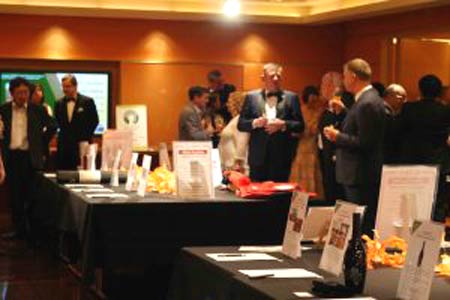 A group of people are standing around tables in a room.