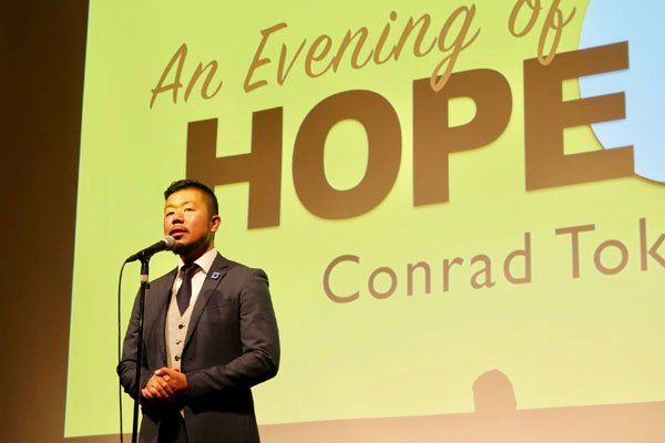 A man is standing in front of a screen that says an evening of hope