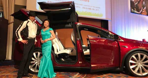 A man and a woman are standing next to a red car.