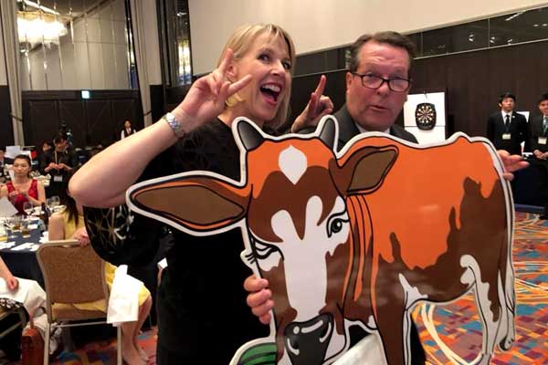 A man and a woman are holding a picture of a cow