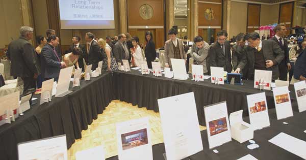 A group of people are standing around a long table with signs on it.