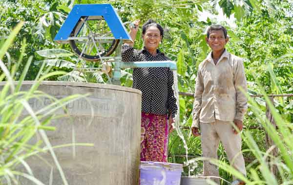 A man and a woman are standing next to a water pump.