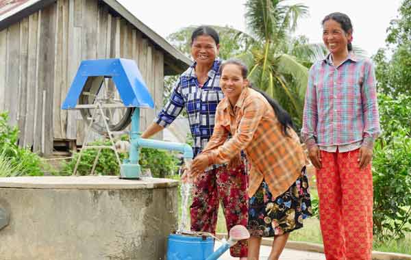 Three women are pumping water from a well.