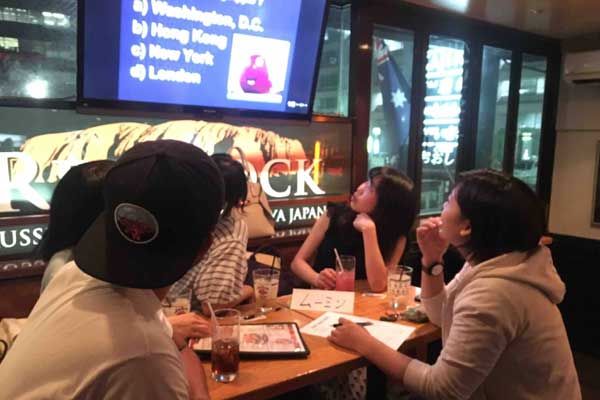 A group of people are sitting at a table in front of a ck sign