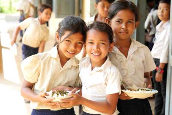 A group of young girls are posing for a picture while holding plates of food.