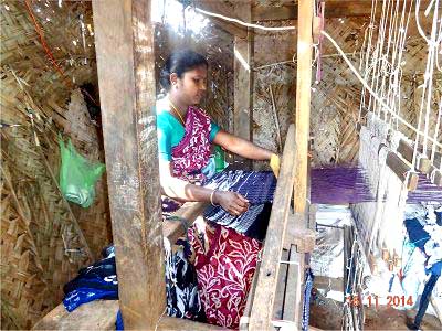 A woman is working on a loom in a hut.
