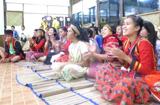 A group of people are sitting on the floor clapping their hands.