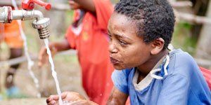 A young boy is washing his hands under a faucet.