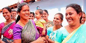 A group of women are standing next to each other and smiling while holding a baby.
