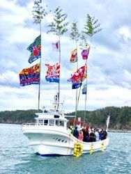 A boat filled with people and flags is floating on top of a body of water.