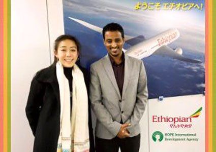 A man and a woman are standing next to each other in front of a poster for ethiopian airlines.