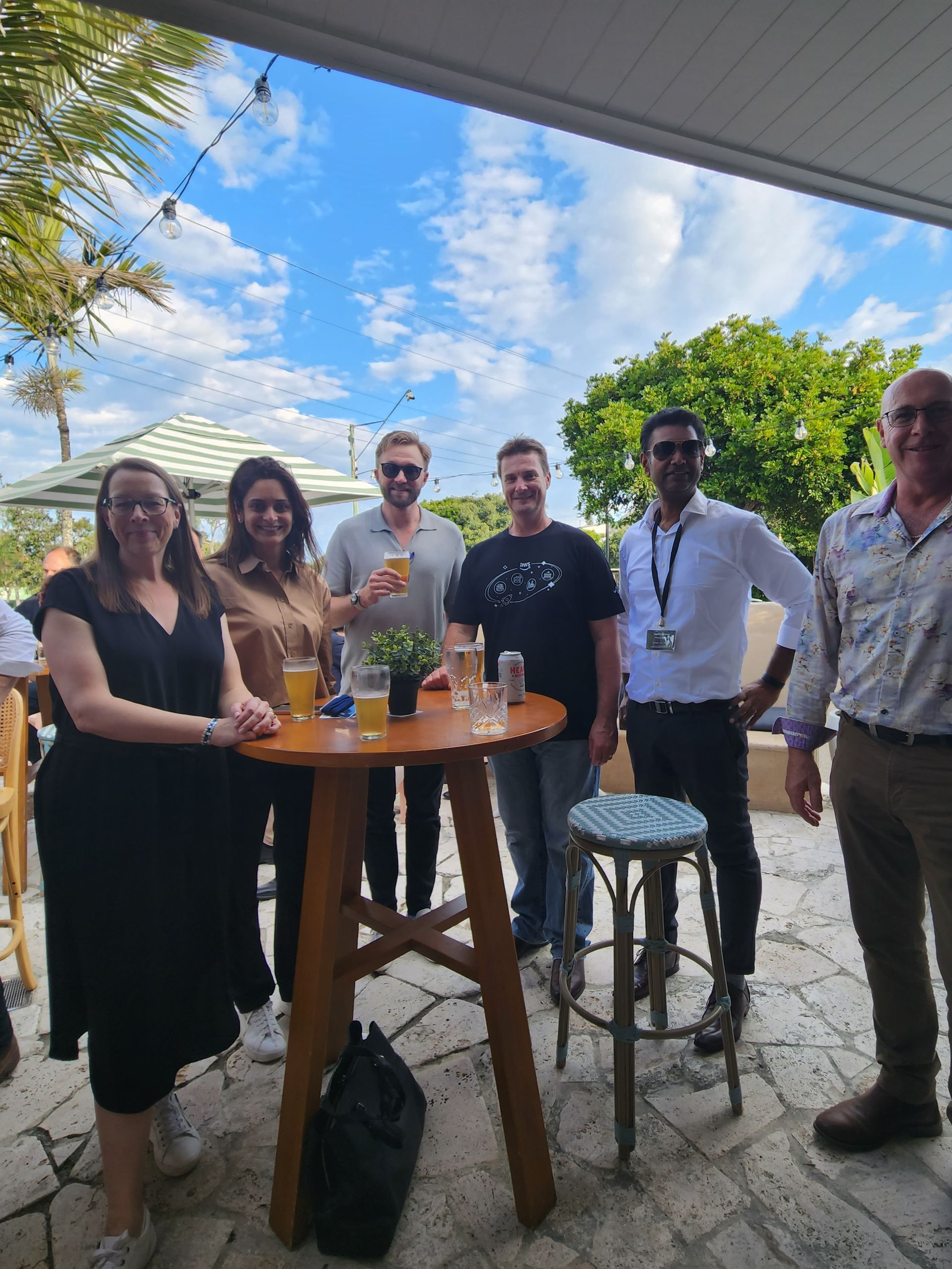 A group of people are standing around a table with drinks on it. LG Innovate AI Summit 2024.
