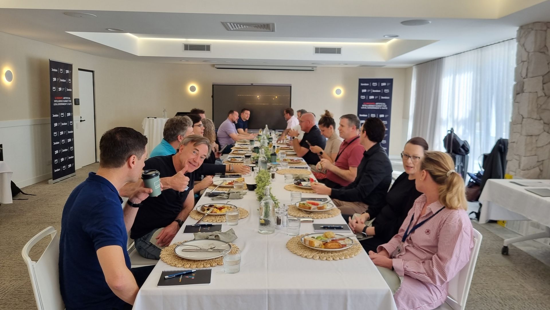 A group of people are sitting at a long table eating food. LG Innovate AI Summit 2024.