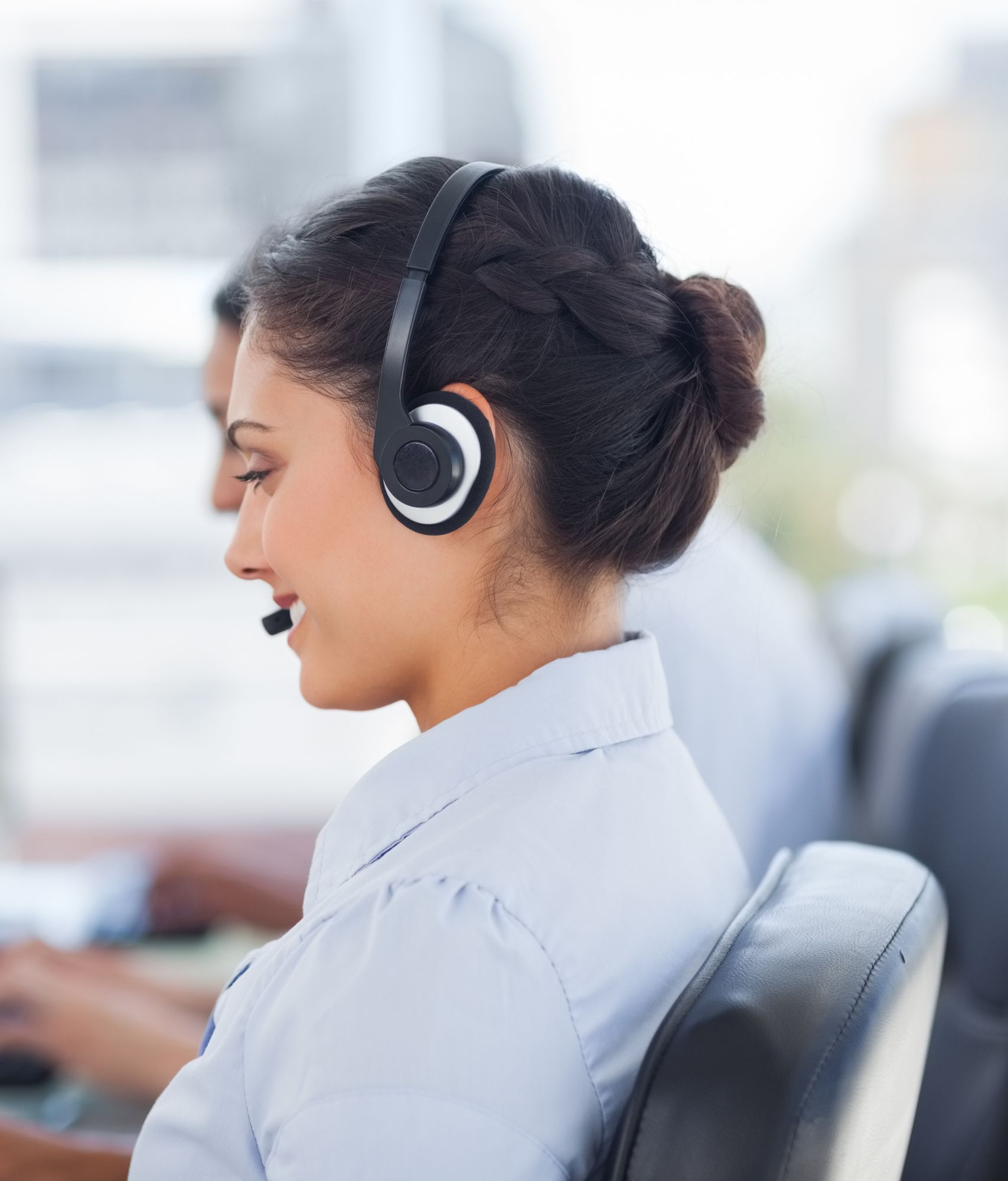 Smiling woman wearing a headset in a call cent