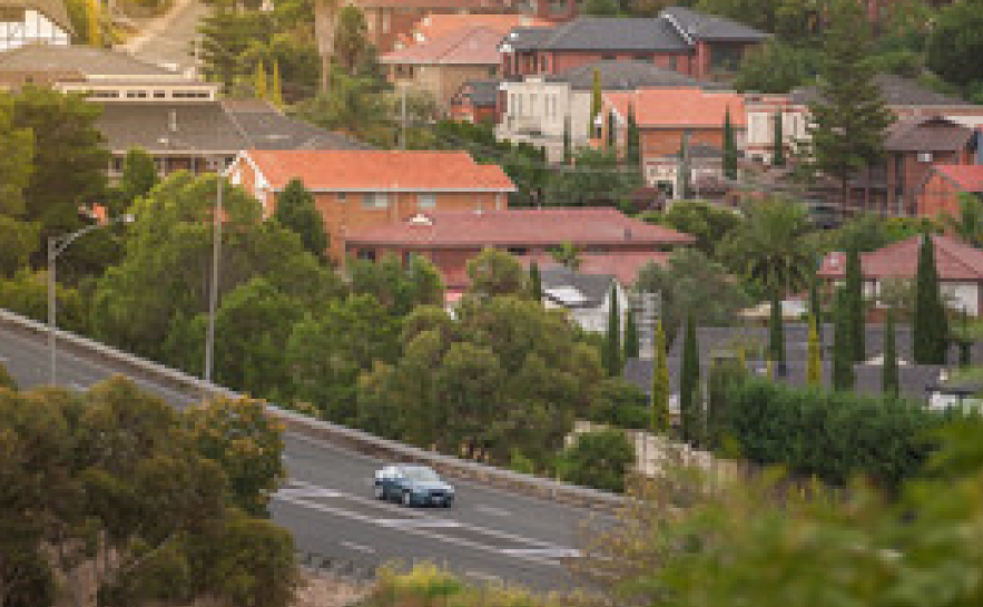 Landscape of many houses and trees beside a main road