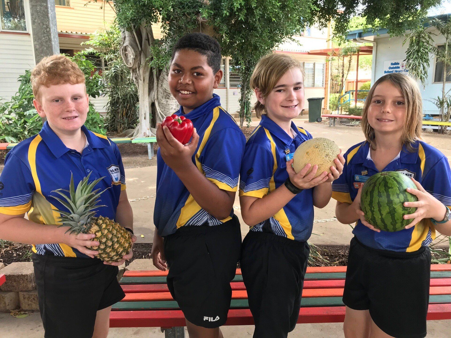 Pick of the Crop kids wearing school uniforms and hold either a fruit or vegetable