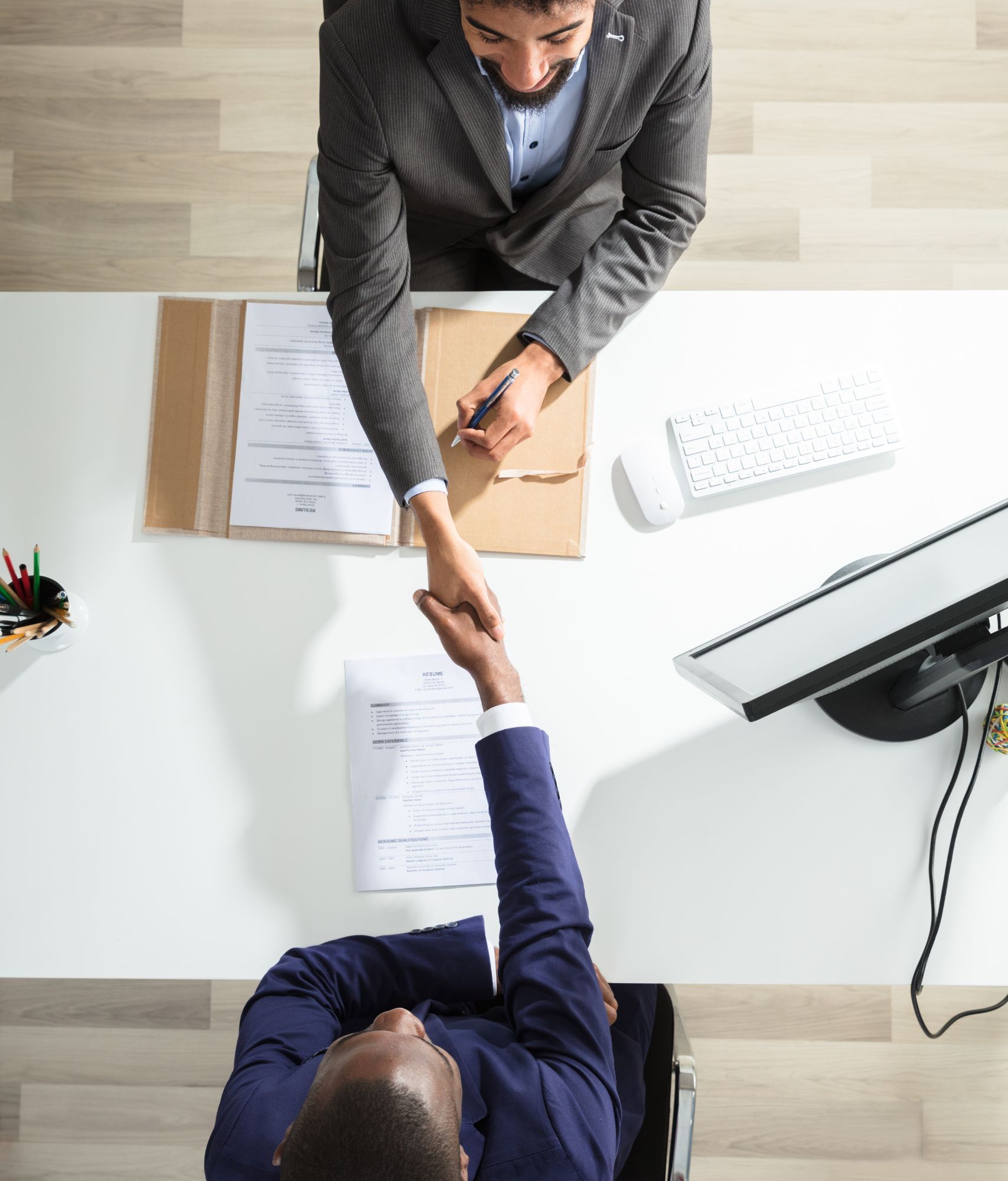 An overhead view of two men shaking hands over a contract.