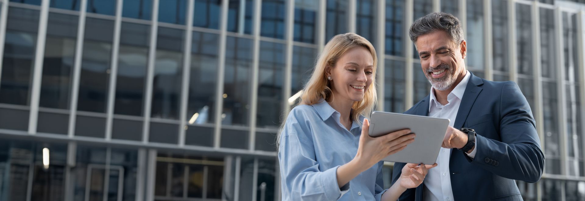 A businessman CEO and a businesswoman are discussing project in front of a building.