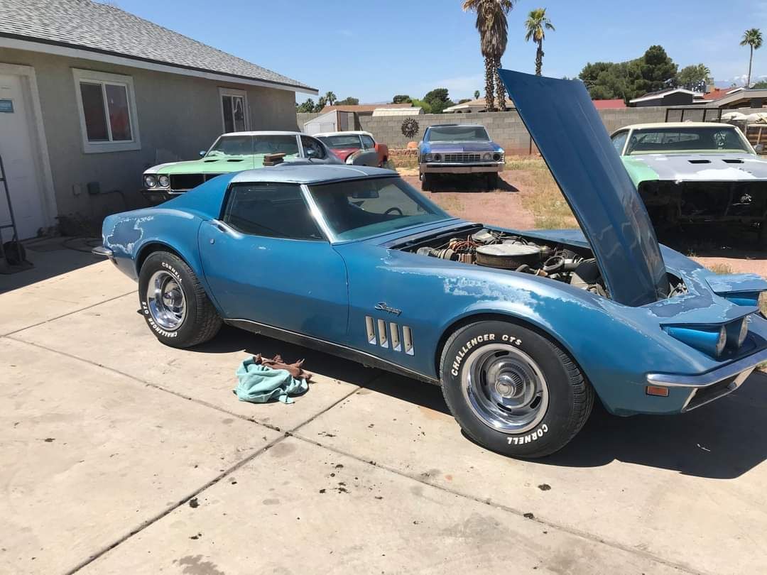 Blue vintage Corvette with open hood, parked in front of a garage. Other classic cars visible in the background. | Don's D.I. Auto & Truck Service