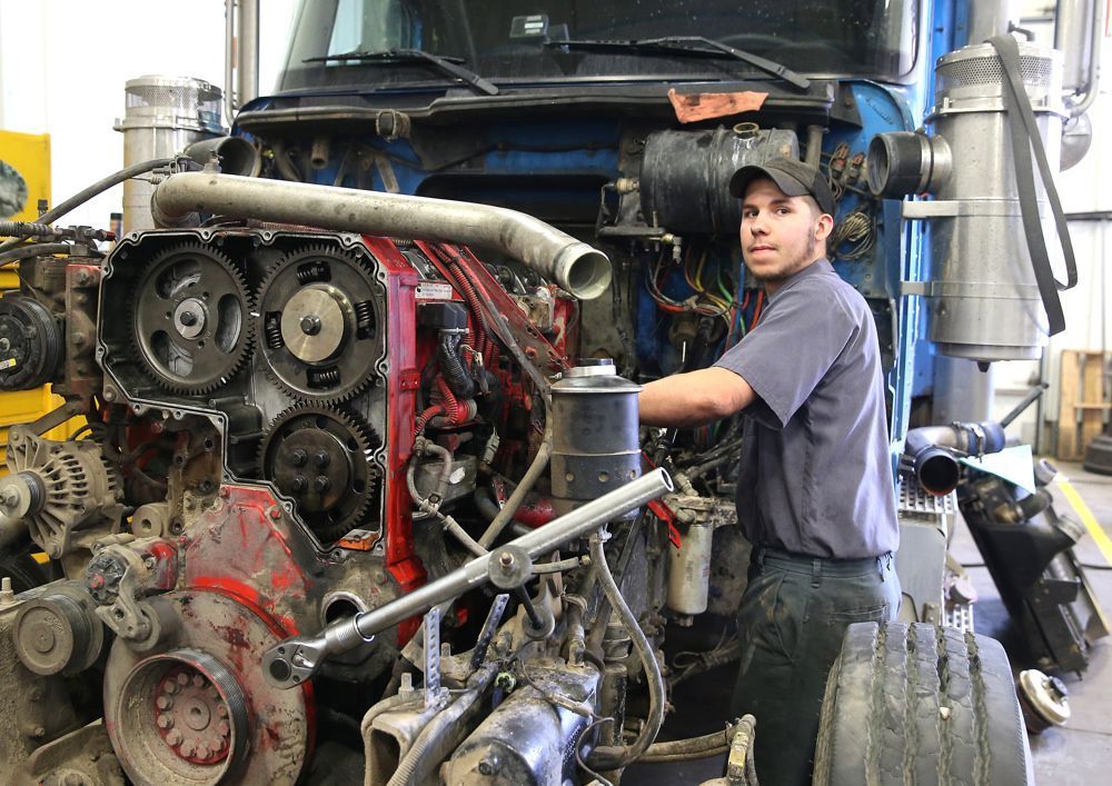 Mechanic holding gears inside an open metal transmission casing; wearing gloves. | Don's D.I. Auto & Truck Service
