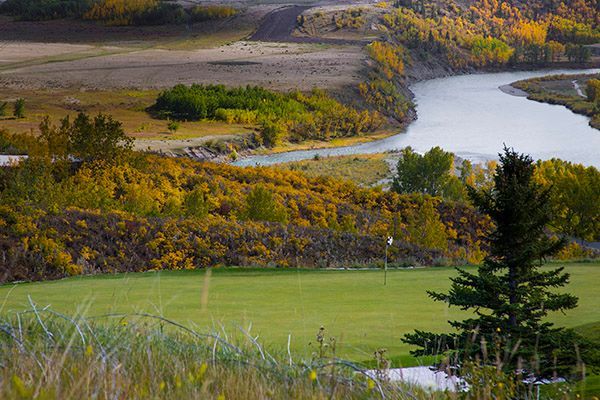 A river winds through a valley with fall foliage and green fields.