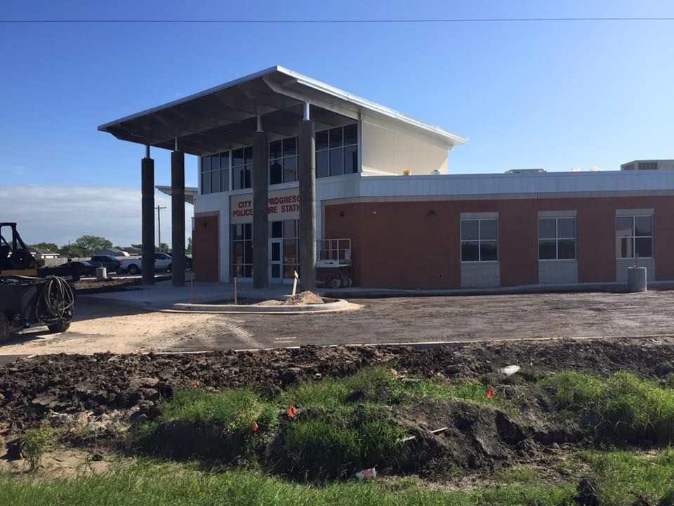 a large brick building is being built next to a dirt road .