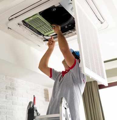 a man is standing on a ladder fixing an air conditioner .