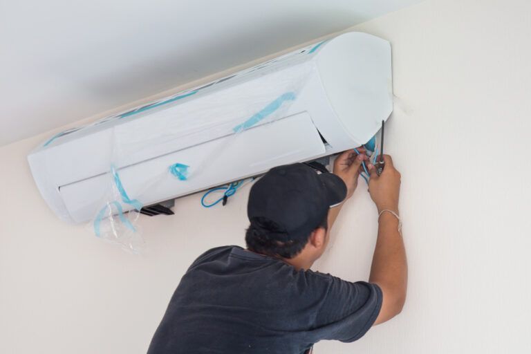 a man is fixing an air conditioner on the wall .