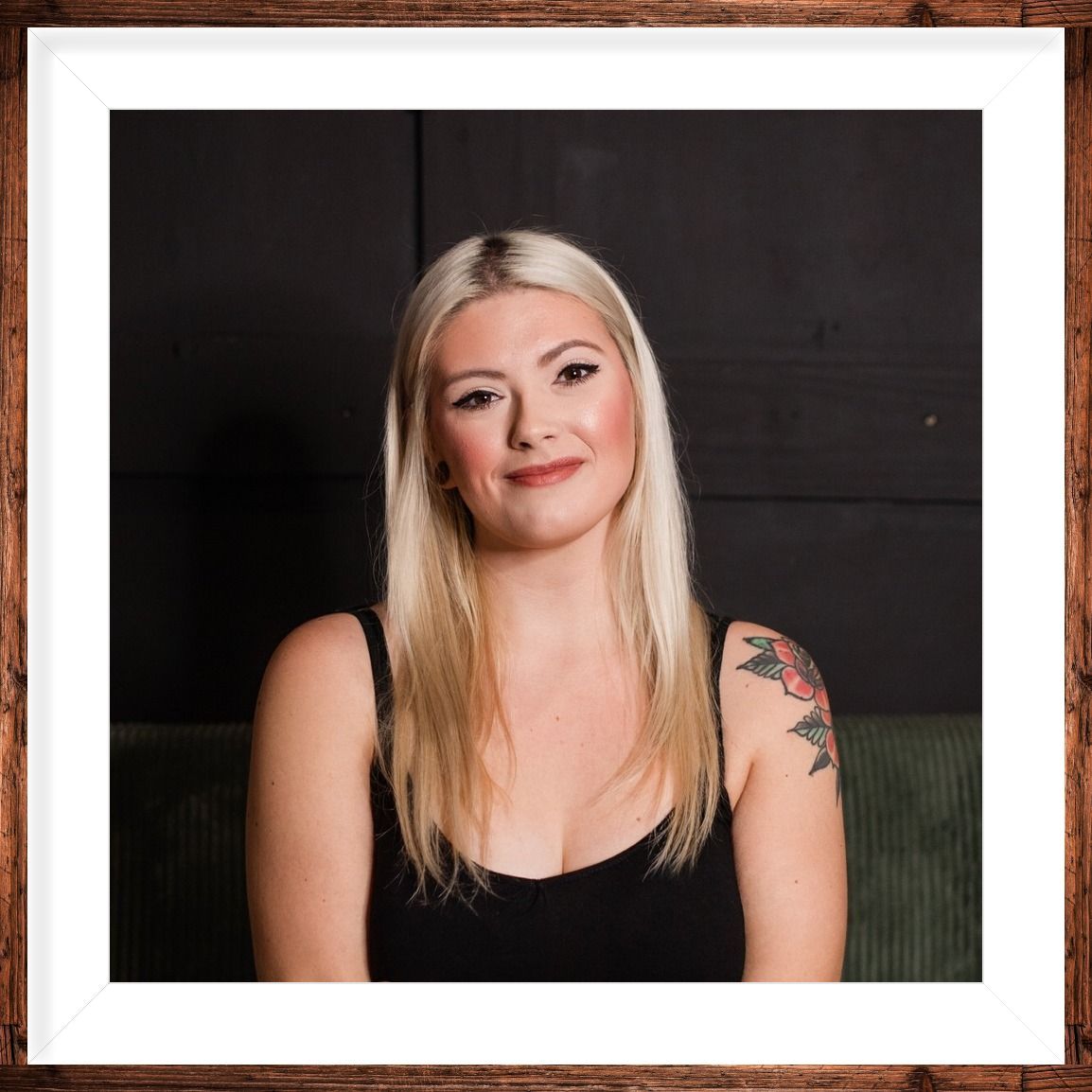 A woman is sitting at a desk with a laptop and a vase of flowers.