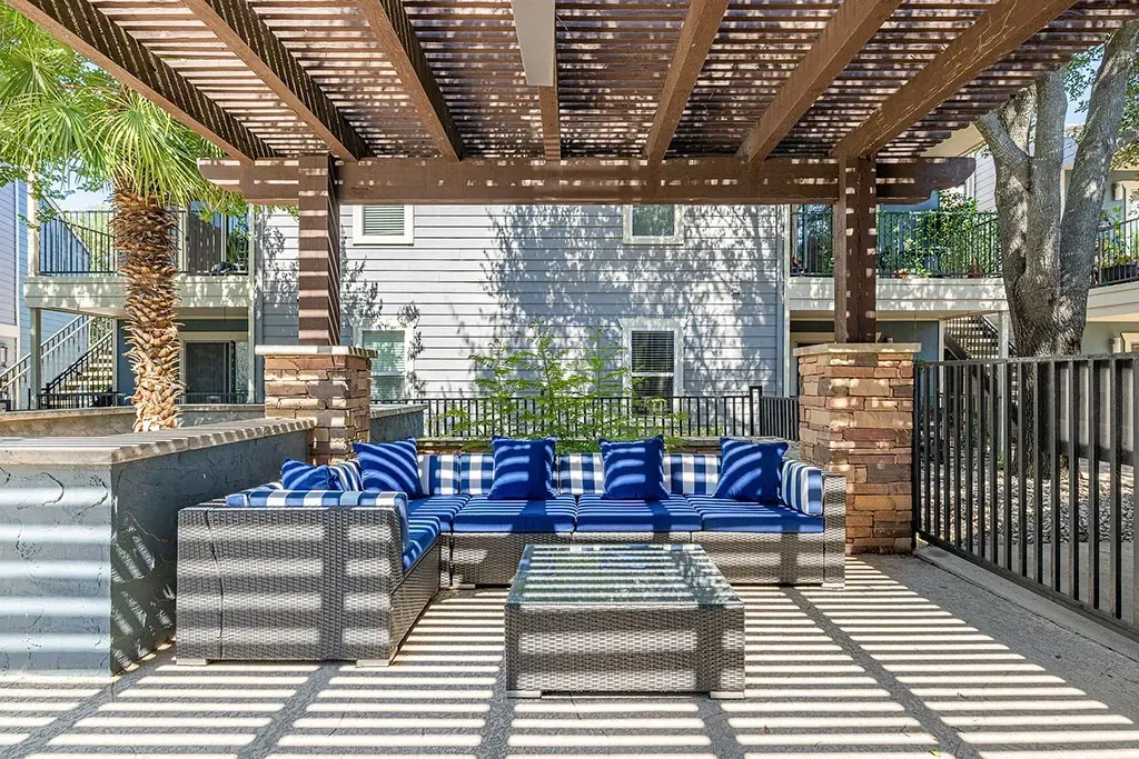 Outdoor lounge area with sectional sofa and coffee table under a pergola.