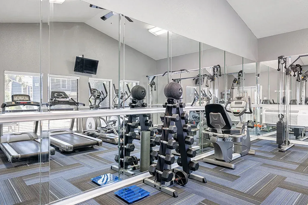 Fitness center with treadmills, elliptical machines, weight rack, and recumbent bike.