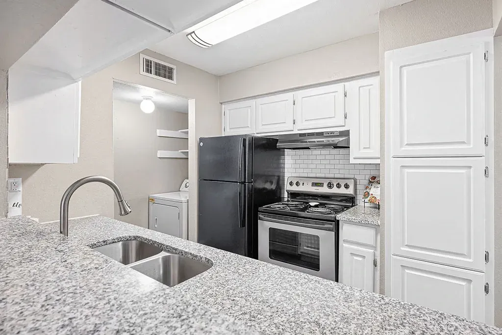 Modern kitchen with granite countertops, stainless steel appliances, and white cabinets.