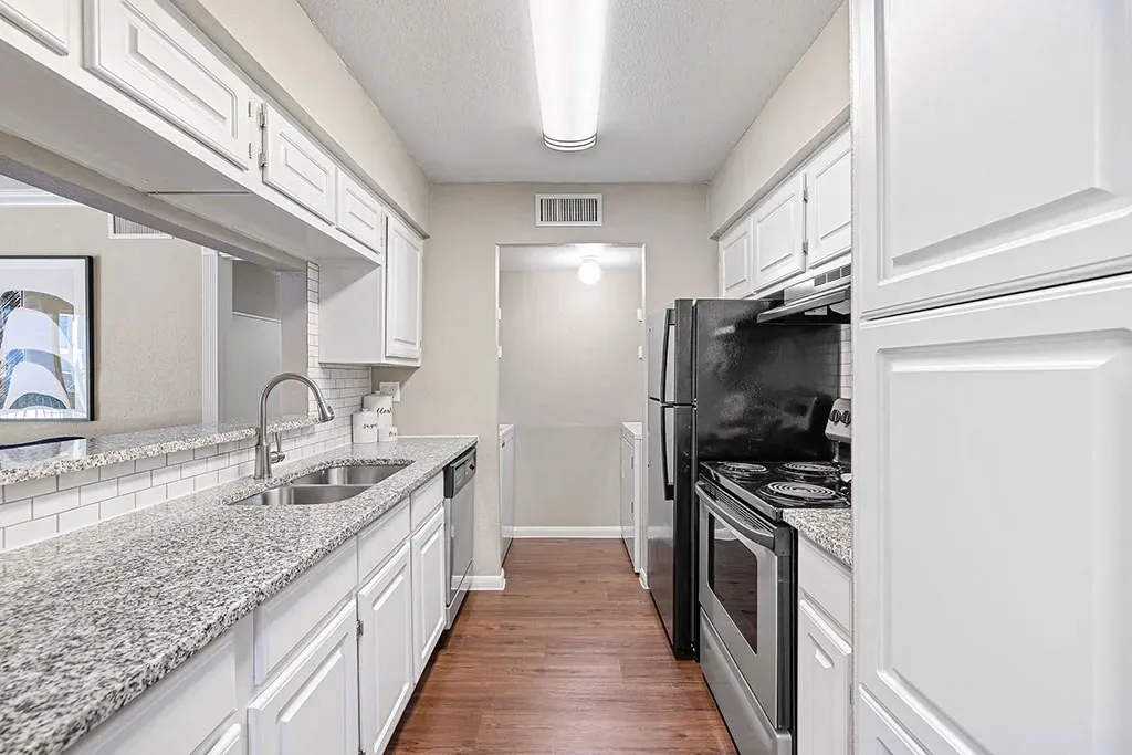 Modern kitchen with white cabinets, granite countertops, and stainless steel appliances.