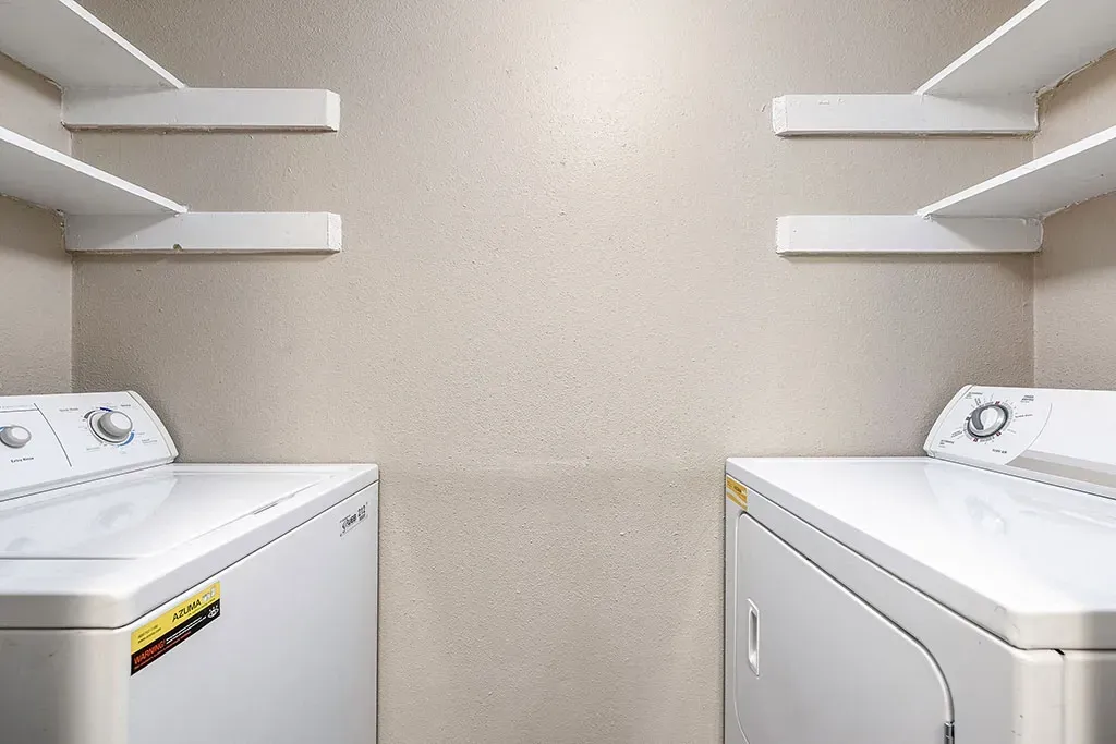 In-unit washer and dryer with shelving above.