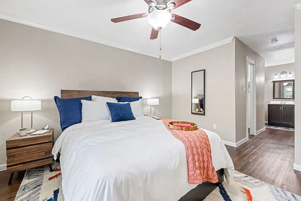 Modern bedroom with a queen-size bed, nightstand, and ceiling fan.