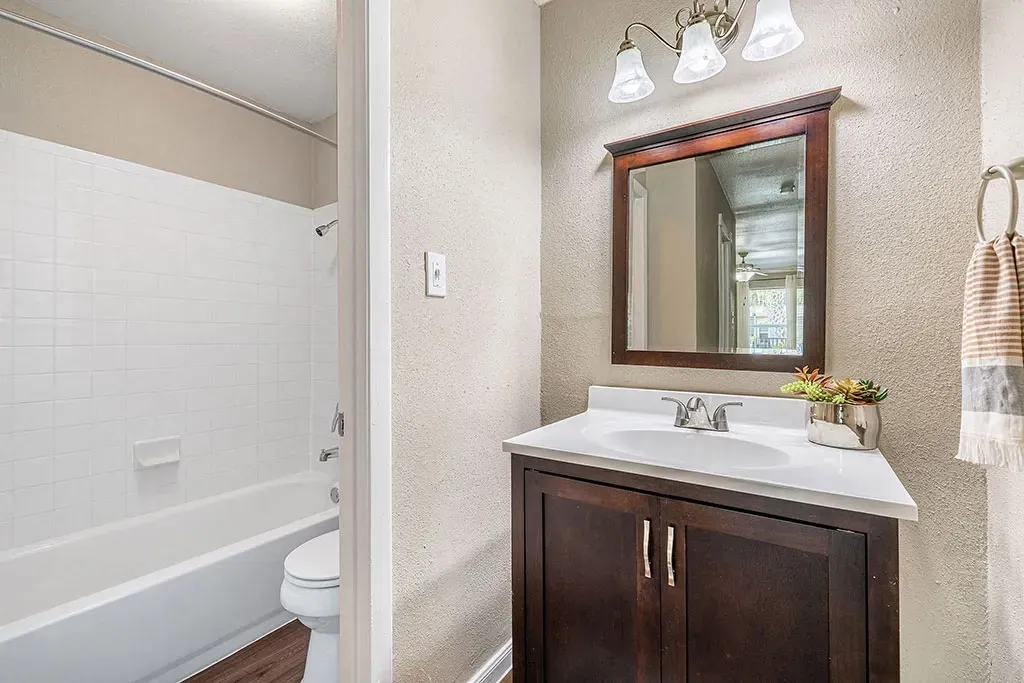 Modern bathroom with a dark wood vanity, white countertop, and white tiled shower/tub.
