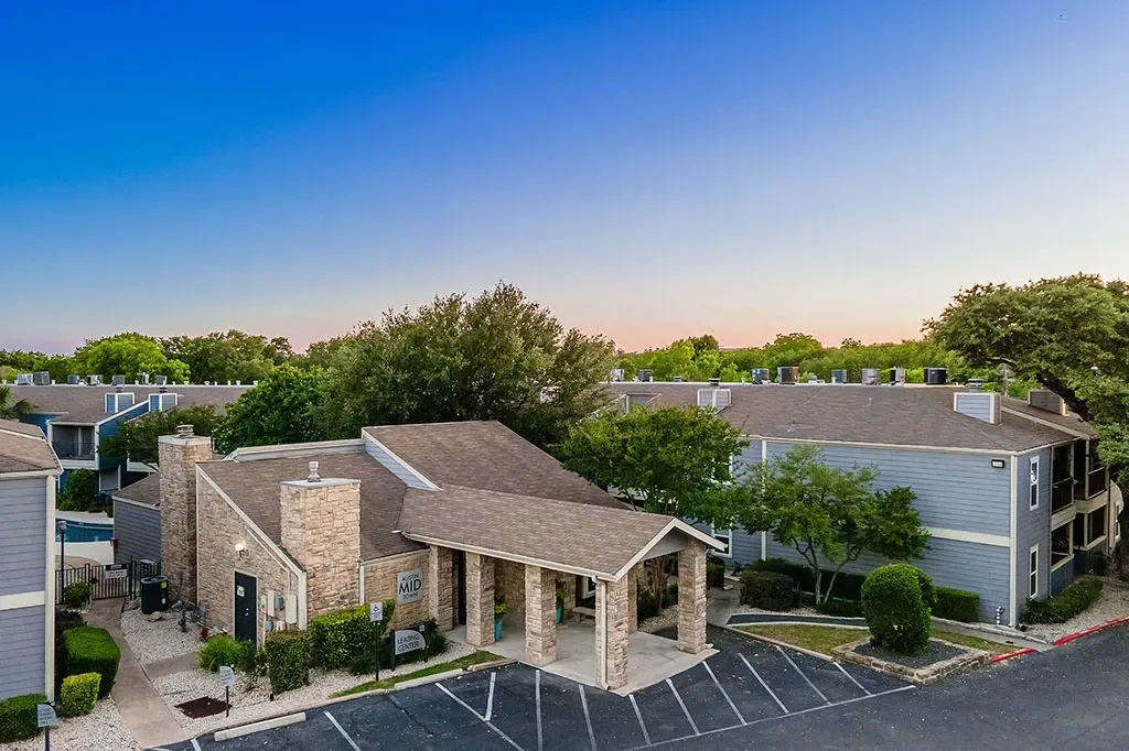 Exterior view of the apartment complex with the leasing center and pool visible.