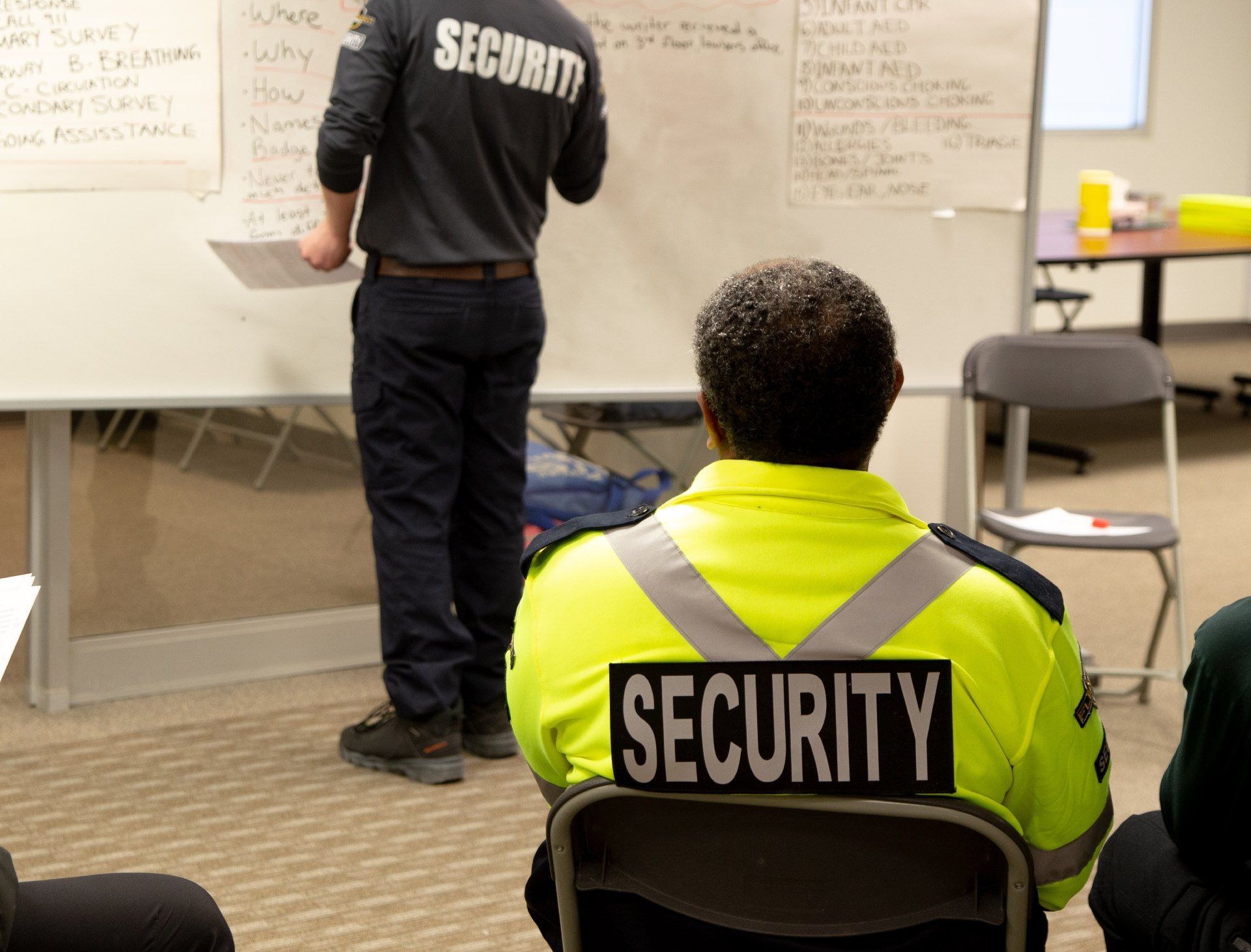 A security guard is sitting in front of a white board