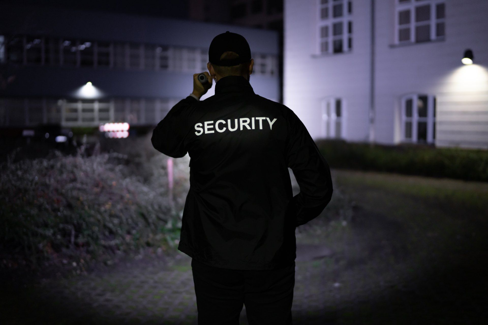 A security guard is talking on a cell phone in front of a building.