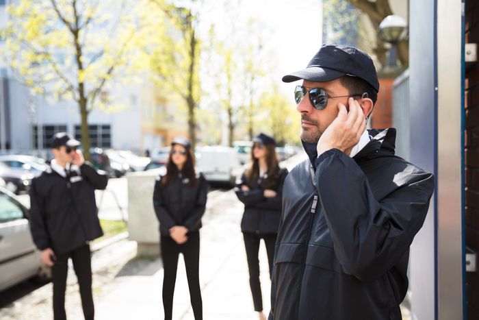 A man is talking on a cell phone while standing next to a group of security guards.