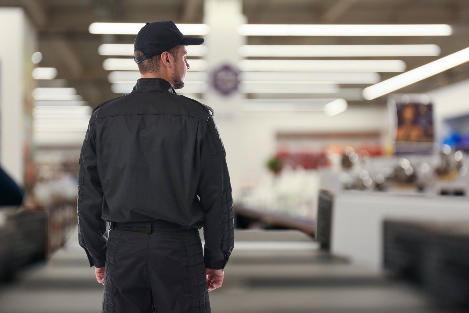 A security guard is standing in a store looking at something.