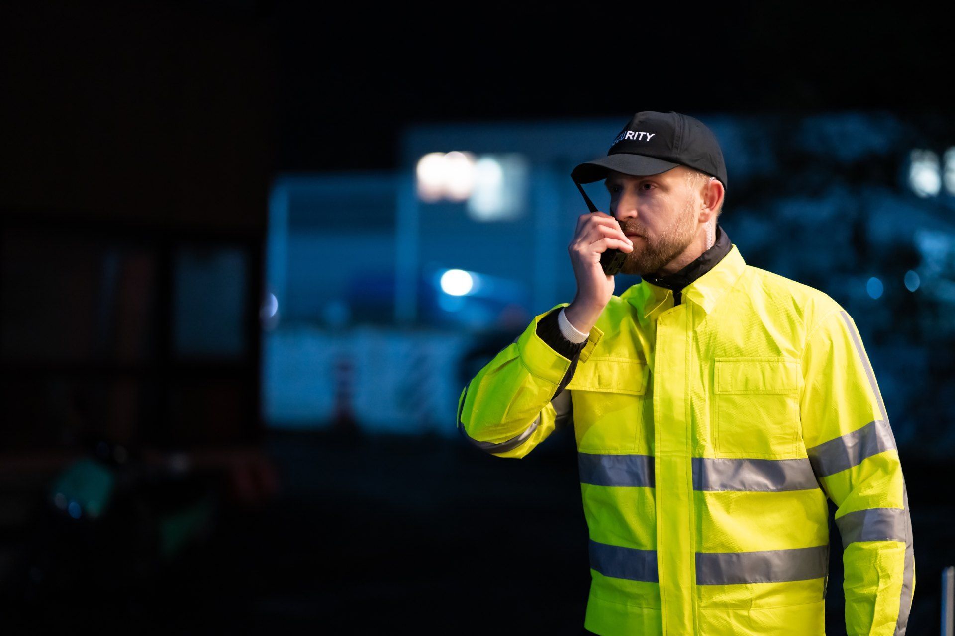 A man in a yellow jacket is talking on a walkie talkie.