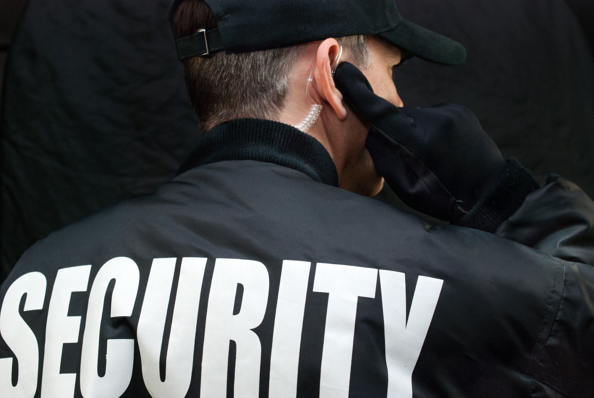 A man wearing a black jacket with the word security on it