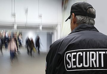 A security guard is standing in front of a crowd of people.