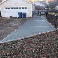 A concrete driveway leading to a garage next to a house.