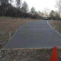 A concrete driveway with a red cone on the side of it.