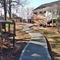 There is a concrete walkway leading to a house.
