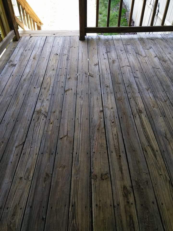 A wooden deck with a railing and stairs in the background.