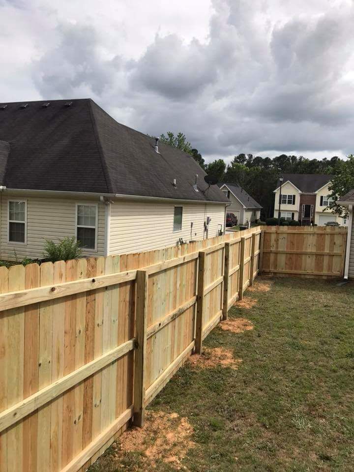 A wooden fence is in the backyard of a house.