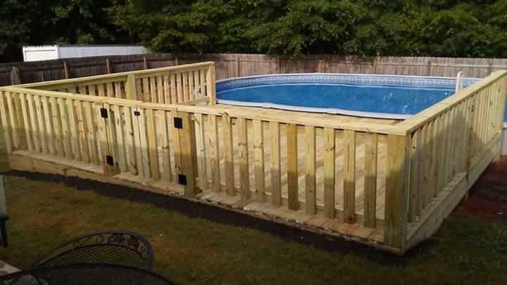 A wooden deck surrounding a swimming pool in a backyard.